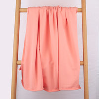 A light pink Tissu French Terry en coton extensible de Longan Craft France est élégamment drapé sur une échelle en bois, mettant en valeur sa texture douce et confortable, idéale pour confectionner des vêtements de sport.