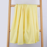 Le Tissu French Terry en coton extensible de Longan Craft France, idéal pour vêtements de sport, est présenté drapé sur une échelle en bois contre un mur clair, mettant en valeur sa texture douce et ses plis élégants.