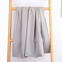 Le Tissu French Terry en coton extensible au mètre de Longan Craft France, un tissu tricoté multicolore confortable idéal pour vêtements de sport, repose sur les barreaux d'une échelle en bois clair devant un mur blanc texturé.