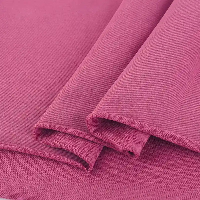 Gros plan sur le Tissu French Terry en coton extensible au mètre de Longan Craft France, montrant sa texture lisse, son tissage visible et ses bords nets - idéal pour les sweatshirts et les vêtements de sport. Multicolore tricoté et confortable.