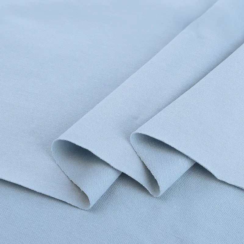 Le Tissu French Terry en coton extensible au mètre de Longan Craft France est présenté à plat avec une texture douce et des bords légèrement pliés-parfait pour les vêtements de sport et projets créatifs.