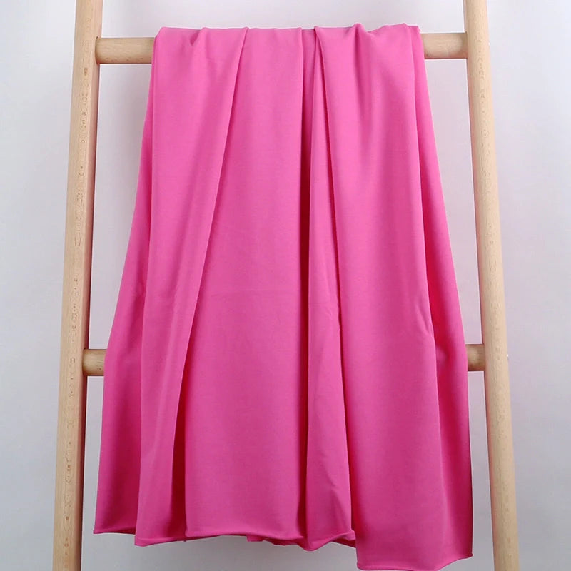 Un tissu extensible French Terry coloré de Longan Craft France est présenté drapé sur une échelle en bois léger, parfaite pour les vêtements de sport.