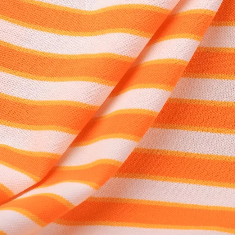 Un gros plan du tissu piqué de coton rayé au mètre de Longan Craft France montre des rayures orange, blanches et bleues avec un pli visible, mettant en valeur la texture tricolore extensible - un tissu de bricolage parfait pour coudre des t-shirts.