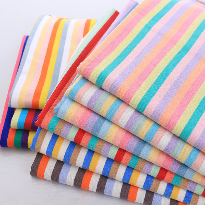 Une pile de Tissu jersey rayé au mètre de Longan Craft France-jersey coton élasthanne extensible, rayures colorées en jaune, rouge, bleu, vert, orange, et rose-matière confortable idéale pour t-shirts manches courtes DIY.