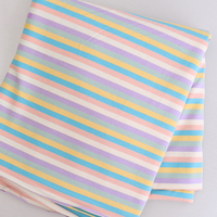 Tissu jersey rayé au mètre de Longan Craft France, en coton élasthanne extensible, présente des rayures pastel diagonales bleu, jaune, rose, violet et blanc-parfait pour confectionner des t-shirts manches courtes DIY.