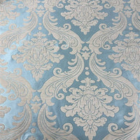 Gros plan sur le Tissu chenille damassé épais au mètre de Longan Craft France, qui présente un motif floral et de volutes beige vintage sur fond bleu clair - un tissu jacquard idéal pour une décoration intérieure raffinée ou des projets de tapisserie d'ameublement.