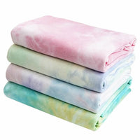 Une pile de tissus pastel en coton French Terry tie-dye de Longan Craft France - rose, vert, bleu clair, sarcelle - sont pliés et soigneusement disposés sur un fond blanc. Idéal pour la confection de vêtements, ce tissu confortable est vendu au mètre.