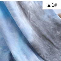 Gros plan sur un tissu bleu clair et gris Tissu French Terry en coton tie-dye au mètre de Longan Craft France, avec de doux motifs nuageux. Une boîte blanche présente un triangle noir et "1#". Parfait pour sweatshirts et vêtements confortables.