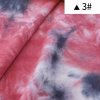 Gros plan sur le Tissu French Terry en coton tie-dye au mètre de Longan Craft France, montrant des nuances de rose, de blanc et de gris foncé. Une étiquette blanche avec un triangle noir et "3#" apparaît dans le coin. Idéal pour vêtements confortables comme les sweatshirts.