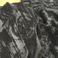 Un gros plan du tissu velours damassé au mètre de Longan Craft France montre son tissage jacquard floral subtil et sa finition légèrement brillante, idéale pour la confection de vêtements aux motifs classiques tourbillonnants et rosés.