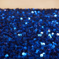 Gros plan sur des paillettes bleues brillantes cousues sur le Tissu en velours extensible à paillettes de Longan Craft France, créant un effet scintillant et réfléchissant, idéal pour les vêtements de scène et la mode.