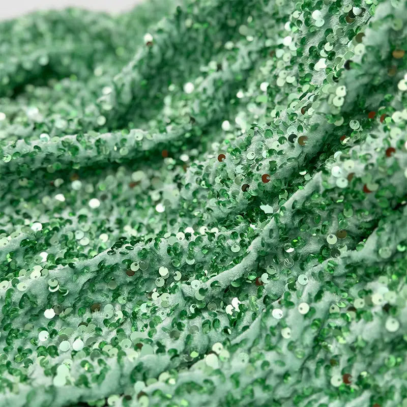 Un gros plan du tissu en velours extensible à paillettes au mètre de Longan Craft France montre des paillettes brillantes densément emballées, créant une surface texturée et réfléchissante, idéale pour les vêtements de scène et la mode.