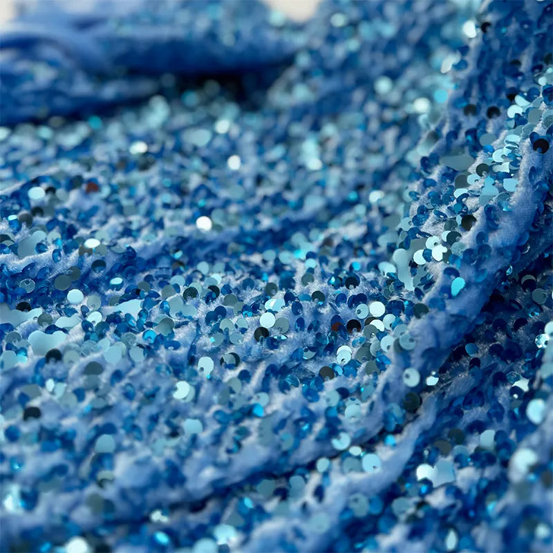 Gros plan sur des paillettes bleues densément cousues sur du Tissu en velours extensible à paillettes au mètre de Longan Craft France, créant un effet texturé et scintillant - idéal pour les vêtements de scène éblouissants et les projets de mode chic.