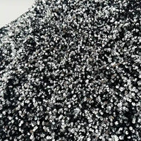 Un gros plan du tissu en velours extensible à paillettes de Longan Craft France montre des paillettes argentées et noires densément emballées sur un tissu extensible, créant un aspect brillant et texturé, idéal pour les costumes de scène et la mode.