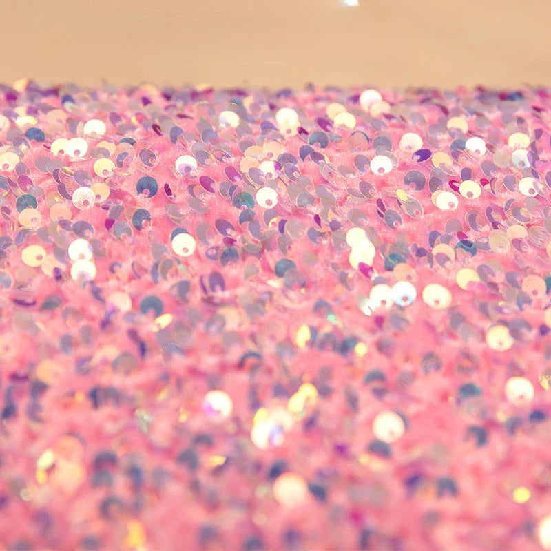 Un gros plan du Tissu en velours extensible à paillettes au mètre de Longan Craft France montre des paillettes roses et violettes scintillantes sur du velours extensible, créant un effet étincelant idéal pour les vêtements de scène et la mode.