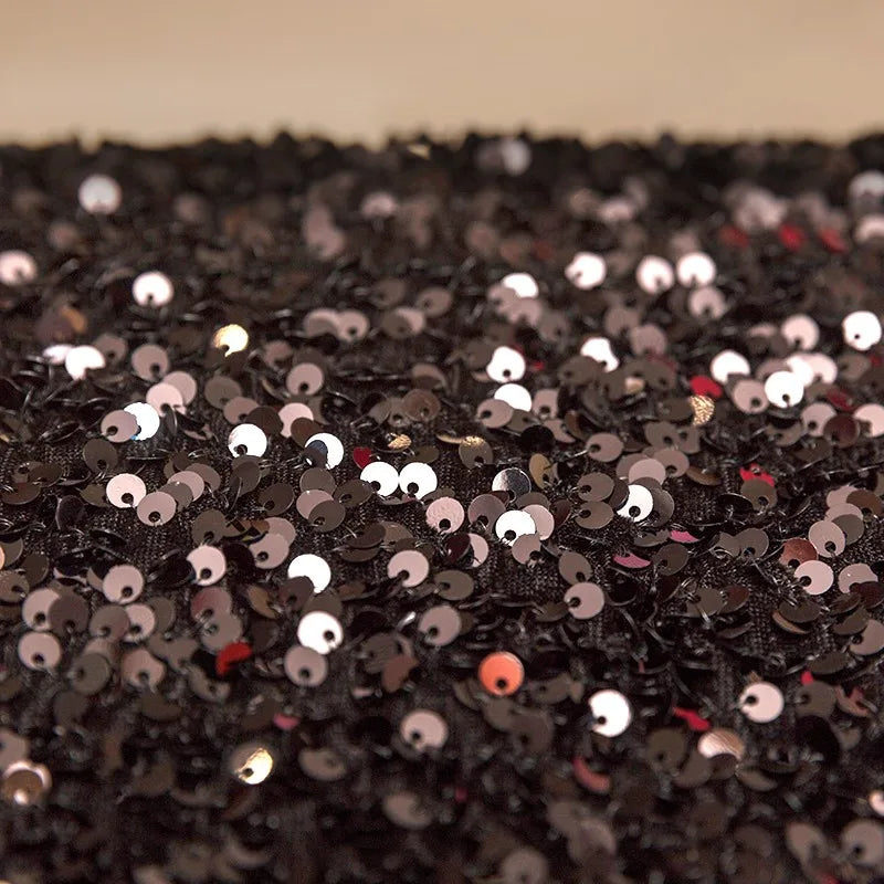 Un gros plan du Tissu en velours extensible à paillettes au mètre de Longan Craft France montre des paillettes noires brillantes et denses sur un velours extensible étincelant, se chevauchant pour couvrir la surface et créer un effet chatoyant - idéal pour les costumes de scène et la mode.