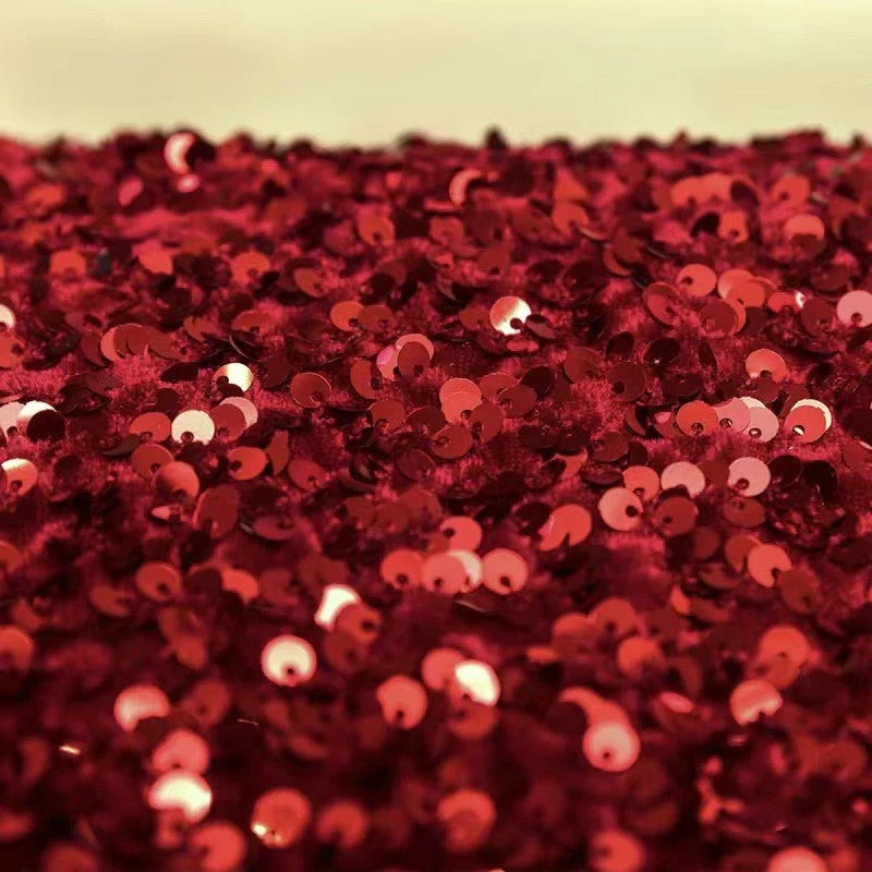 Gros plan sur les paillettes rouges brillantes et denses du Tissu en velours extensible à paillettes au mètre de Longan Craft France, qui reflètent la lumière pour un effet scintillant - idéal pour les costumes de scène et les vêtements à la mode.