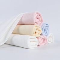 Cinq tissus doux à pointelle roulée de Longan Craft France dans des tons pastel - blanc, rose, jaune et bleu - empilés avec un drapé, idéal pour le bricolage d'intérieur avec notre Tissu pointelle côtelé vertical au mètre.