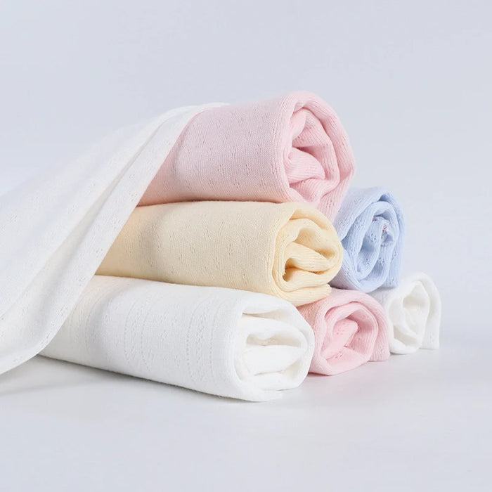 Cinq tissus doux à pointelle roulée de Longan Craft France dans des tons pastel - blanc, rose, jaune et bleu - empilés avec un drapé, idéal pour le bricolage d'intérieur avec notre Tissu pointelle côtelé vertical au mètre.