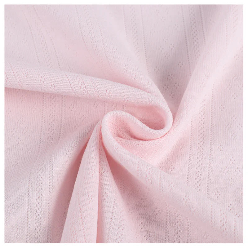 Gros plan sur le tissu pointelle côtelé vertical au mètre de Longan Craft France, un tissu polyester rose pâle aux rayures subtiles et aux motifs délicats, légèrement froncé pour montrer son drapé - idéal pour les vêtements d'intérieur DIY.