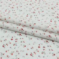 Gros plan sur le Tissu plumetis rouge à motifs floraux au mètre de Longan Craft France, un tissu de coton vintage aux imprimés floraux et à pois, présenté dans des plis délicats.