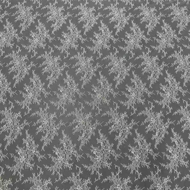 Une délicate dentelle florale blanche, évoquant la dentelle blanche française, orne un tissu gris transparent dans un motif Chantilly régulier. Parfaite pour le bricolage nuptial, cette dentelle à bords festonnés de Longan Craft France est vendue au mètre pour les robes de mariée élégantes.