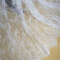Gros plan sur la dentelle Chantilly blanche au mètre de Longan Craft France, une dentelle de mariage française florale aux bords festonnés, avec des détails complexes et des mailles transparentes, parfaite pour les robes de mariée DIY.