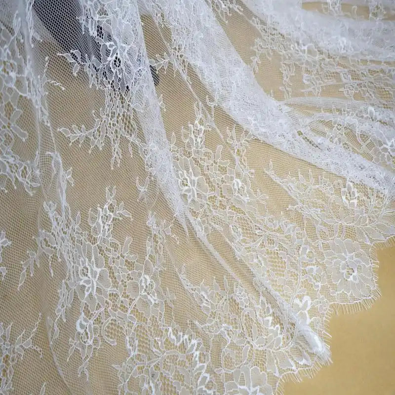 Gros plan sur la dentelle Chantilly blanche au mètre de Longan Craft France, une dentelle de mariage française florale aux bords festonnés, avec des détails complexes et des mailles transparentes, parfaite pour les robes de mariée DIY.