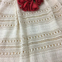Gros plan sur le Tissu dentelle en coton blanc au mètre de Longan Craft France, qui présente des motifs complexes de dentelle jacquard et se drape librement, avec des roses rouges artificielles qui ajoutent du charme, idéal pour les projets de couture DIY.