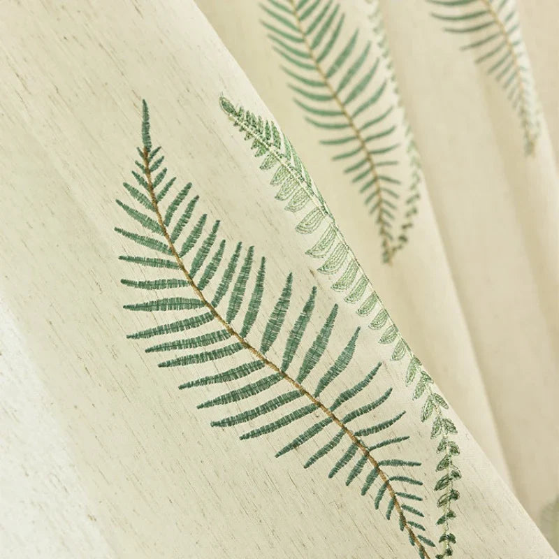 Gros plan sur le tissu de rideau en tulle blanc à motifs feuilles de Longan Craft France, qui présente de délicats motifs botaniques disposés en diagonale sur le tissu transparent et élégant, vendu au mètre.