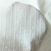Gros plan sur le tissu jacquard à rayures blanches et plumetis au mètre de Longan Craft France, un tissu suisse transparent présentant des rayures blanches et des points en relief régulièrement espacés.
