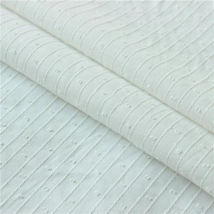 Gros plan sur le tissu jacquard à rayures blanches et plumetis au mètre de Longan Craft France, un tissu suisse transparent à rayures blanches et texture pointillée, présenté plié proprement.