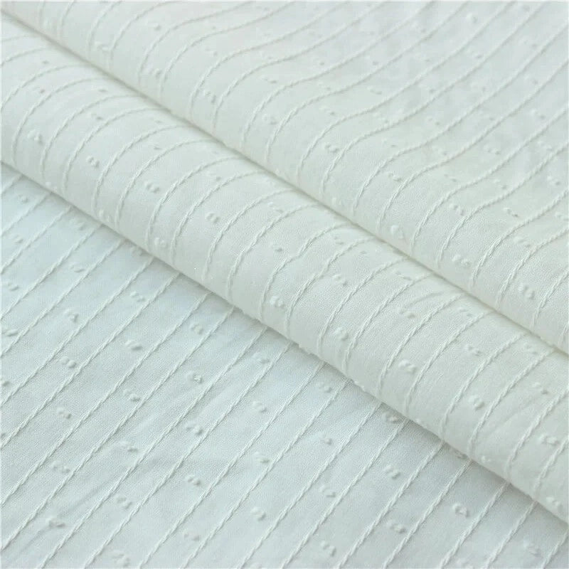 Gros plan sur le tissu jacquard à rayures blanches et plumetis au mètre de Longan Craft France, un tissu suisse transparent à rayures blanches et texture pointillée, présenté plié proprement.