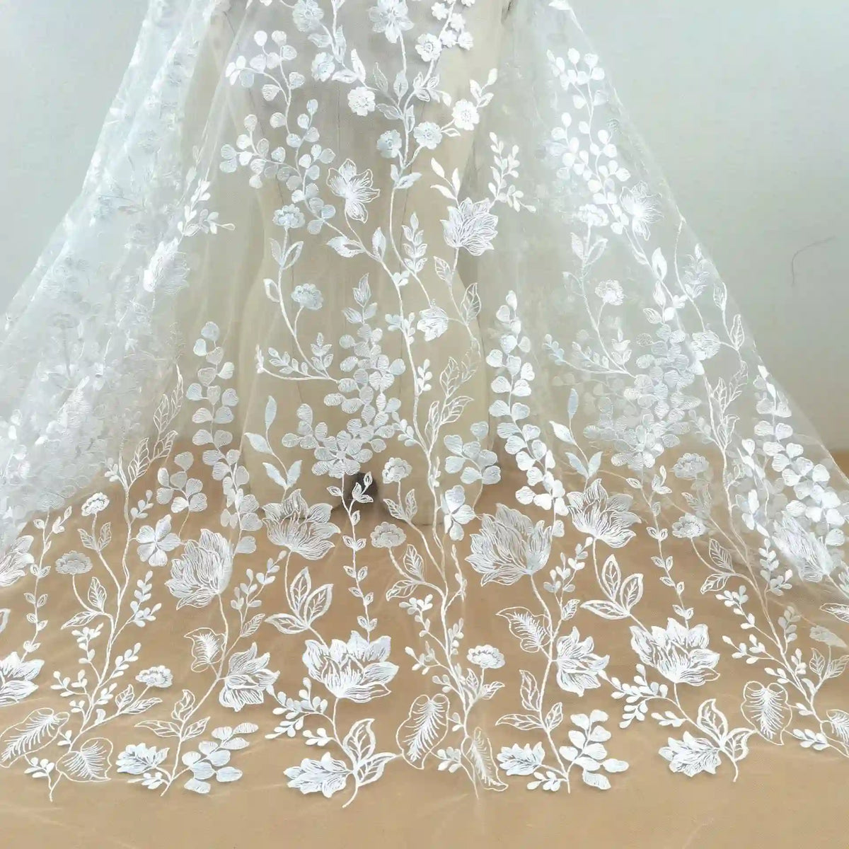 Le Tulle brodé floral blanc au mètre pour couture de robe élégante de Longan Craft France présente une broderie florale délicate, idéale pour créer de superbes robes de cérémonie.