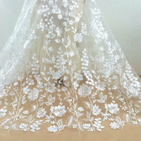 Le Tulle brodé floral blanc au mètre pour couture de robe élégante de Longan Craft France présente une broderie florale délicate, idéale pour créer de superbes robes de cérémonie.