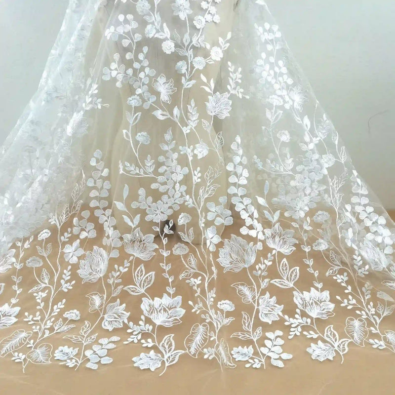Le Tulle brodé floral blanc au mètre pour couture de robe élégante de Longan Craft France présente une broderie florale délicate, idéale pour créer de superbes robes de cérémonie.