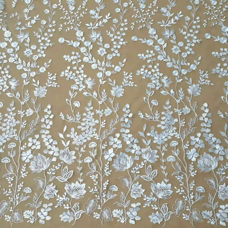 Le tulle brodé floral blanc au mètre de Longan Craft France présente d'élégantes broderies florales blanches dans un motif vertical symétrique sur un tulle marron clair - parfait pour la confection de vêtements de cérémonie élégants.