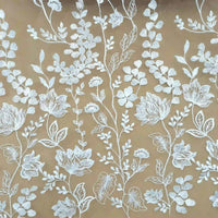 Le Tulle brodé floral blanc au mètre pour couture de robe élégante de Longan Craft France présente une broderie de dentelle florale blanche complexe sur une base marron clair, idéale pour créer des robes de cérémonie élégantes.
