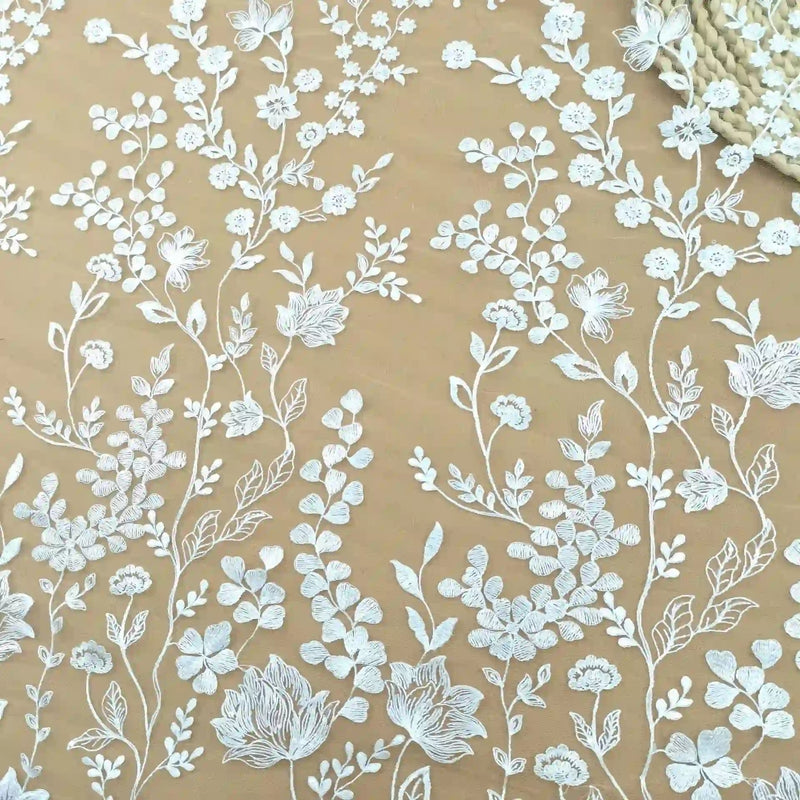 Le Tulle brodé floral blanc au mètre pour couture de robe élégante de Longan Craft France présente une broderie de dentelle florale blanche avec des fleurs et des feuilles sur un tulle transparent beige clair - idéal pour créer des robes de cérémonie élégantes.