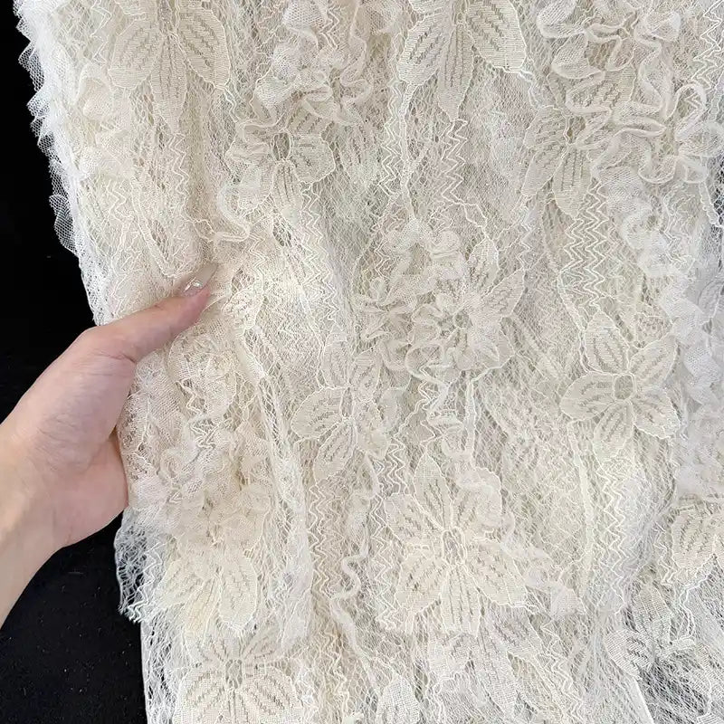 Une main présente le "Tissu en dentelle 3D au mètre" de Longan Craft France, qui présente une broderie et un motif floral - un tissu en dentelle française parfait pour les jupes de printemps et d'été - sur un fond sombre.