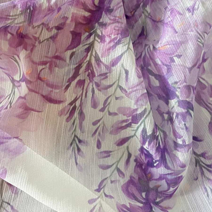 Le Tissu mousseline imprimé fleurs de glycine violettes au mètre de Longan Craft France est une mousseline légère et douce, idéale pour la couture de robes, avec un motif floral délicat et un joli drapé texturé.