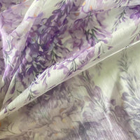 Découvrez le tissu mousseline imprimé fleurs de glycine violettes au mètre par Longan Craft France, un tissu léger et transparent à motif floral violet et vert sur fond blanc, parfait pour des robes élégantes et douces.