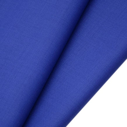 Gros plan sur deux pièces superposées de Tissu gabardine de laine peignée au mètre de Longan Craft France, montrant la surface bleu roi lisse et subtilement texturée - la gabardine sergée en laine-polyester idéale pour les costumes élégants et sur mesure.
