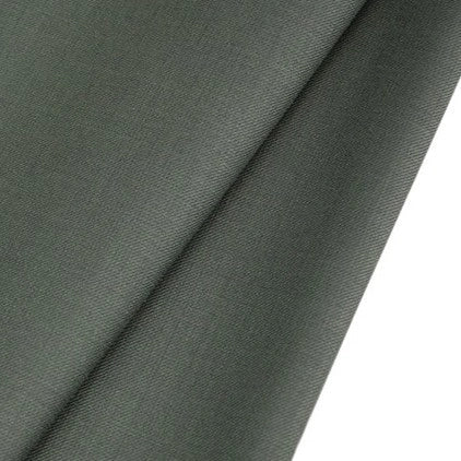 Gros plan sur un Tissu gabardine de laine lisse et gris foncé peigné au mètre de Longan Craft France, un mélange durable de laine et de polyester parfait pour les costumes sur mesure, plié en biais sur un fond blanc uni.