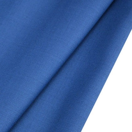 Gros plan sur un tissu bleu lisse, Tissu gabardine de laine peignée au mètre de Longan Craft France, un tissu durable en laine et polyester pour les costumes sur mesure, plié en biais sur un fond blanc.