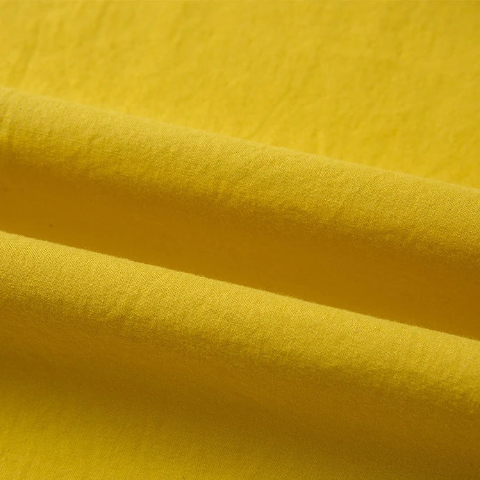 Gros plan sur le Tissu linon de coton tissé au mètre en jaune de Longan Craft France, un tissu de doublure en coton multicolore et ultra-doux montrant ses plis et ombres naturels.