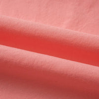 Gros plan sur le tissu linon de coton tissé au mètre de Longan Craft France, d'un rose corail uni, dont les plis délicats mettent en valeur la haute douceur et la texture moelleuse du linon de coton.