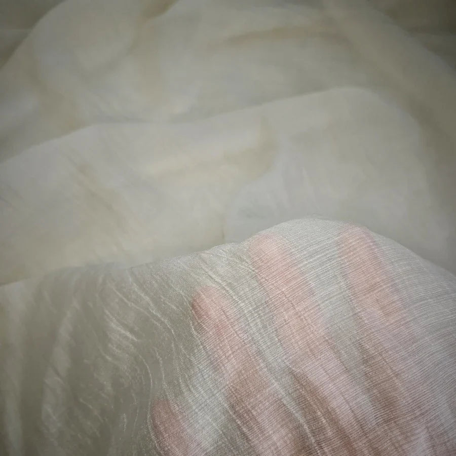 Une main appuie sur le tissu lyocell froissé au mètre de Longan Craft France - un tissu lyocell semi-transparent, léger et respirant qui révèle les contours des doigts et présente une surface douce et délicatement texturée.