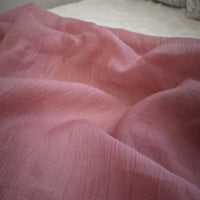 Un gros plan du Tissu lyocell froissé au mètre de Longan Craft France montre un tissu lyocell rose doux et froissé avec une surface légèrement texturée et des plis délicats. Ce textile léger et durable est idéal pour les hauts respirants.