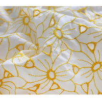 Gros plan sur le Tissu brodé ajouré œillet jaune au mètre de Longan Craft France, un tissu 100 % coton brodé d'œillets floraux jaunes ; l'image bien éclairée met en valeur sa texture et ses détails délicats.